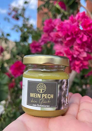 Pechsalbe vor Blumen
